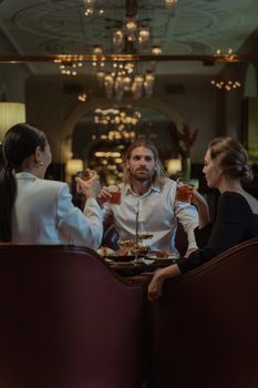 Group of adults toasting drinks in a luxurious restaurant, creating a sophisticated atmosphere.