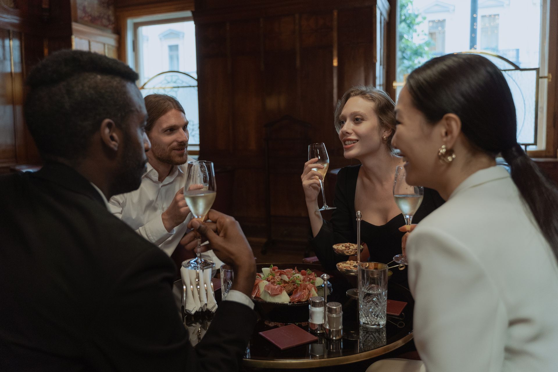 A diverse group of friends enjoying drinks and dinner in a stylish restaurant setting.