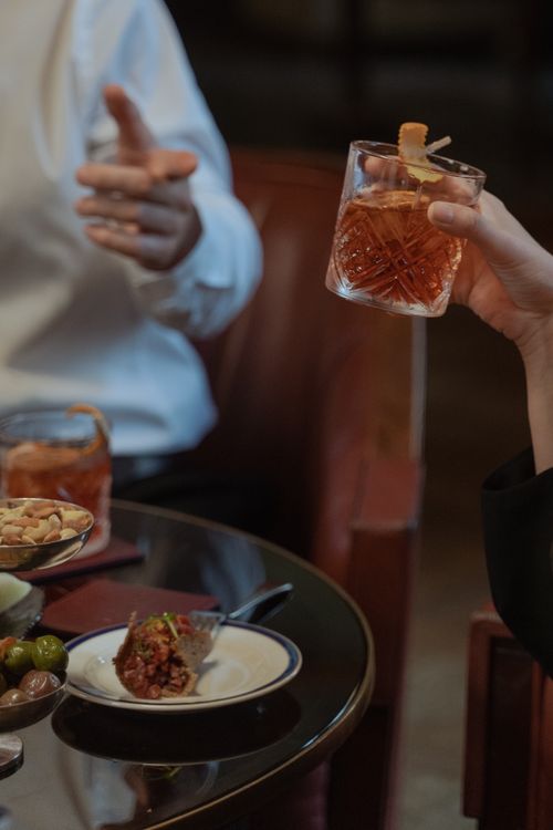 Free An indoor scene of adults enjoying cocktails and appetizers in a relaxed setting. Stock Photo