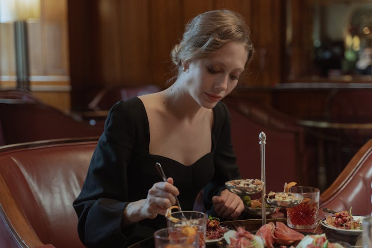 
A Woman Wearing A Black Dress Having Dinner