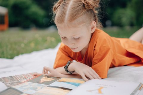Girl reading outdoors on a sunny day — photo by Mikhail Nilov on Pexels