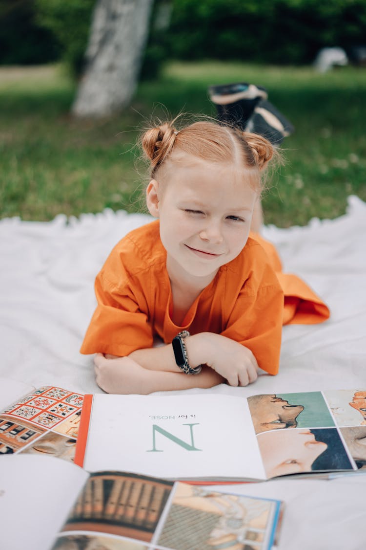 Photo Of A Kid In An Orange Shirt Winking At The Camera