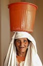 在塞夫鲁，一位老妇人头戴橙色水桶，巧妙展示着文化服装