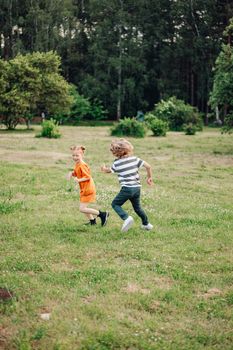 Two children enjoying a carefree day playing in a green field, surrounded by nature.