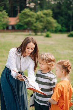 A young teacher reading a book to two children in a park, fostering outdoor education.