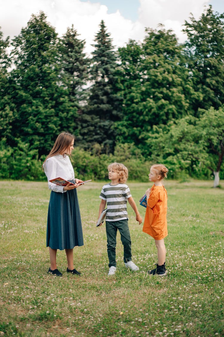 A Woman Talking To The Kids While Standing On The Field