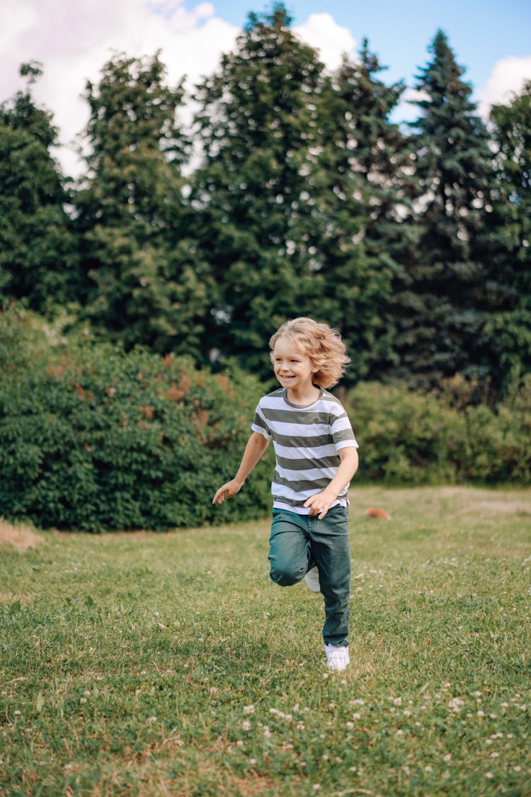 Boy In Striped Shirt Running On Grass Field