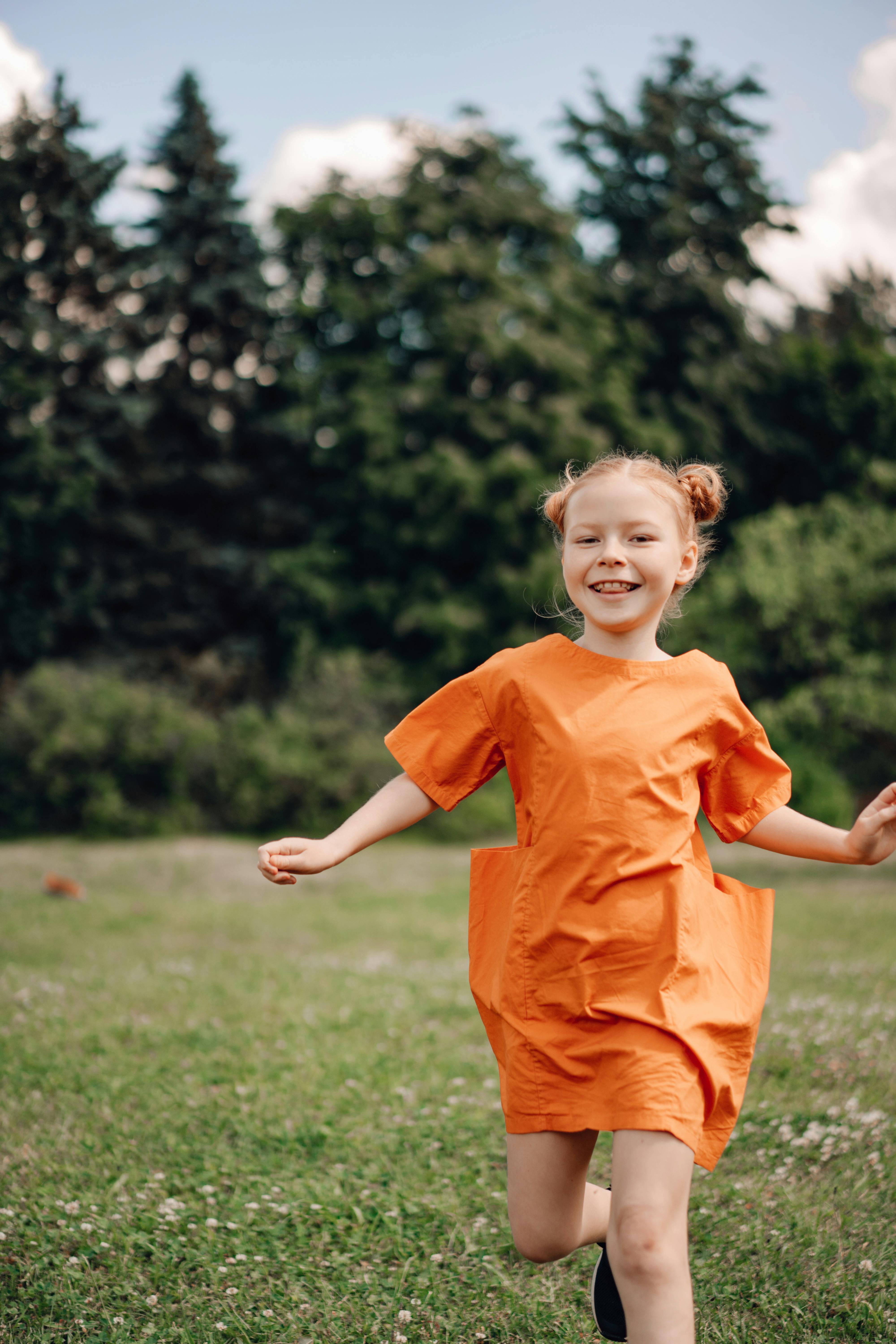 a young girl smiling while running on the field