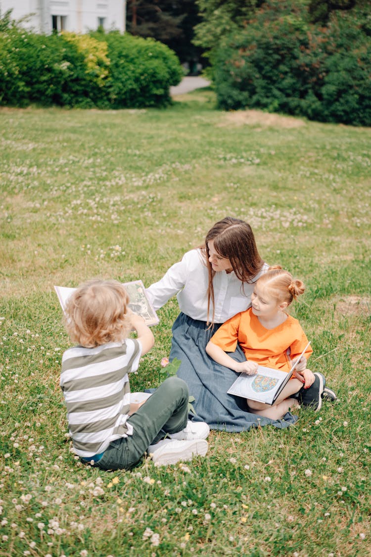 A Woman Sitting At The Park While Talking To The Kids