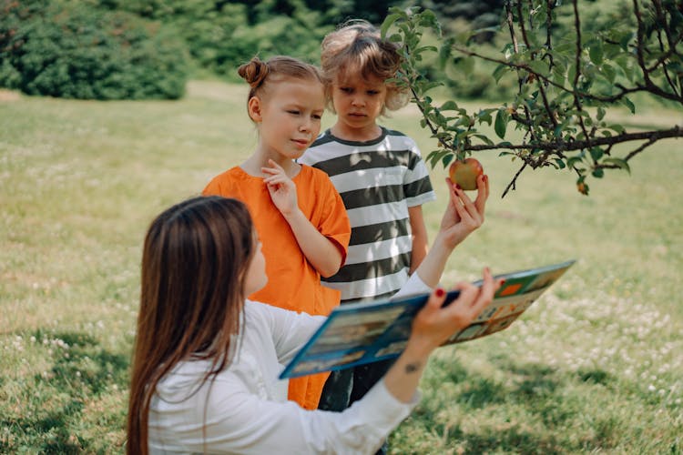 A Teacher Showing The Apple To The Kids