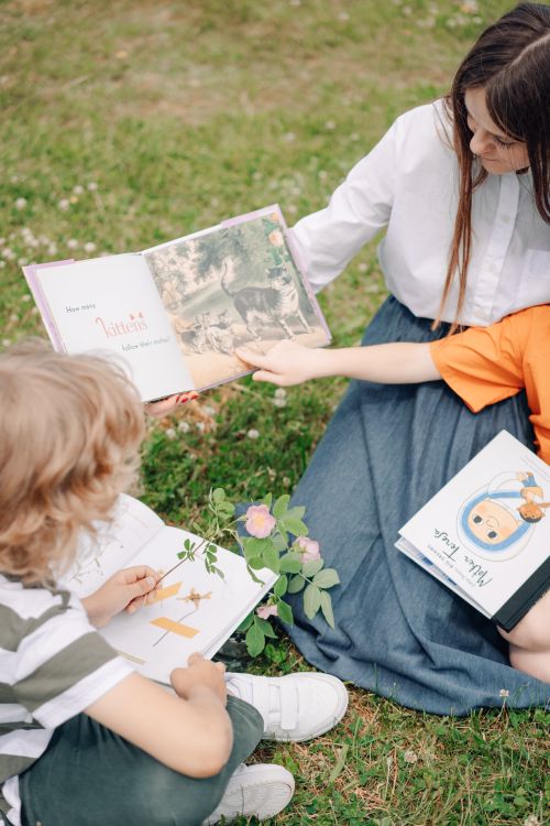 Free Kids reading books together outdoors on a sunny day, enjoying learning and nature. Stock Photo