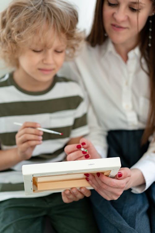 Boy in White and Green Strip Shirt Holding White Paintbrush and White Canvass