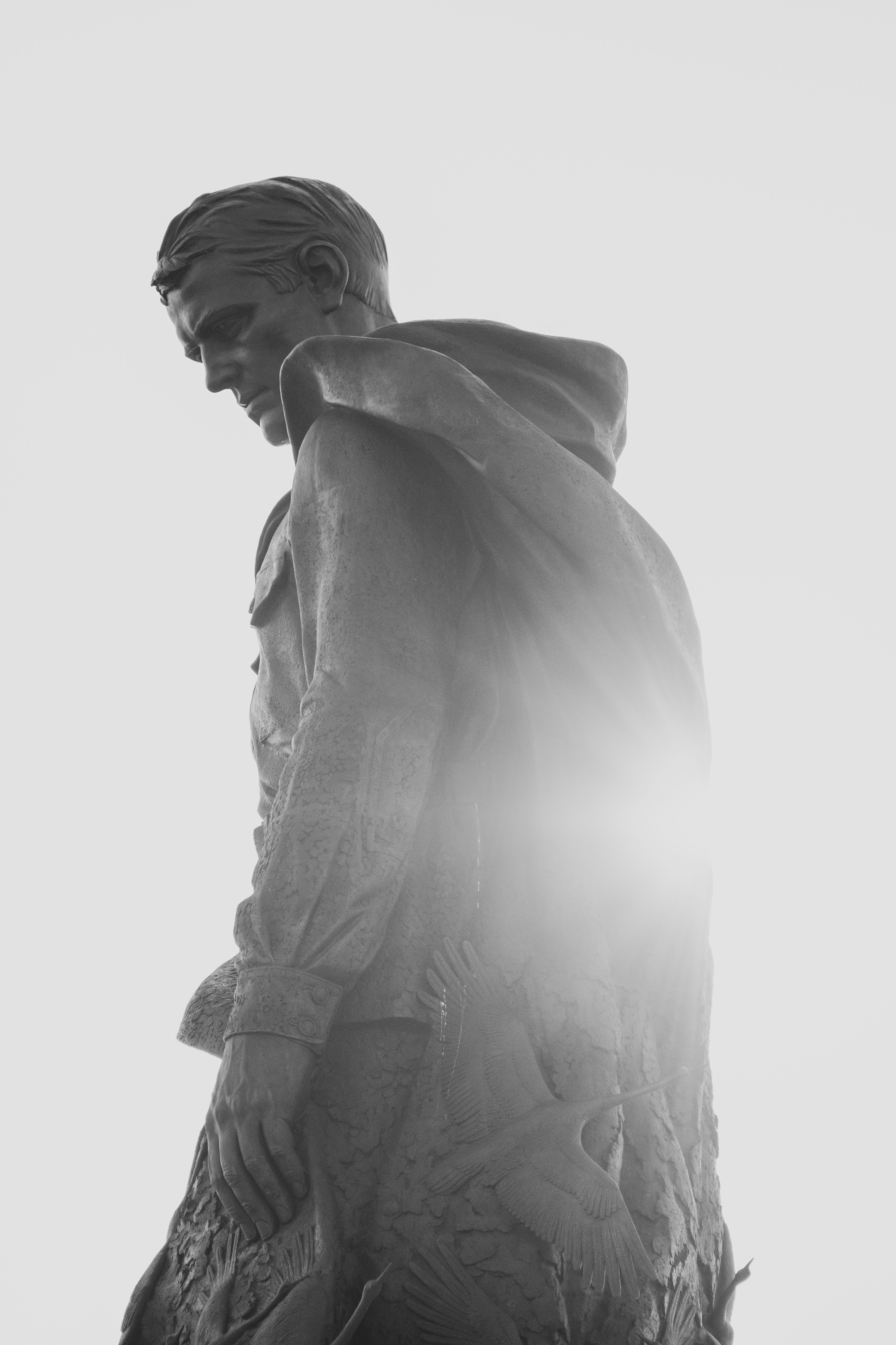 Striking backlit photograph of a monumental statue in grayscale.