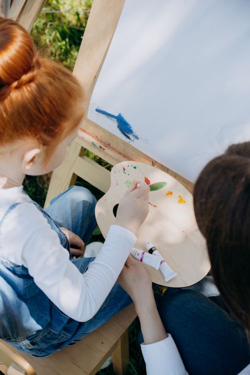 Free A child and a teacher engaged in painting outdoors, fostering creativity and learning. Stock Photo