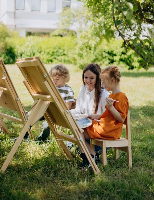 Free Children and teacher painting outdoors, enjoying a creative lesson under a tree. Stock Photo
