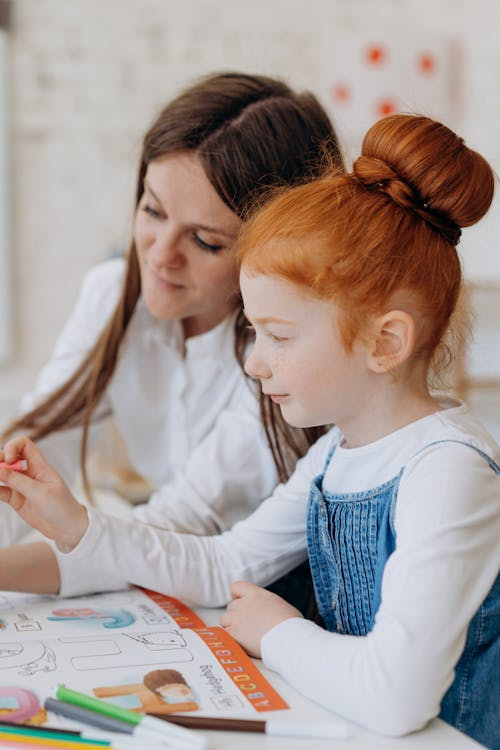 A Cute Little Girl beside a Woman in White Long Sleeves