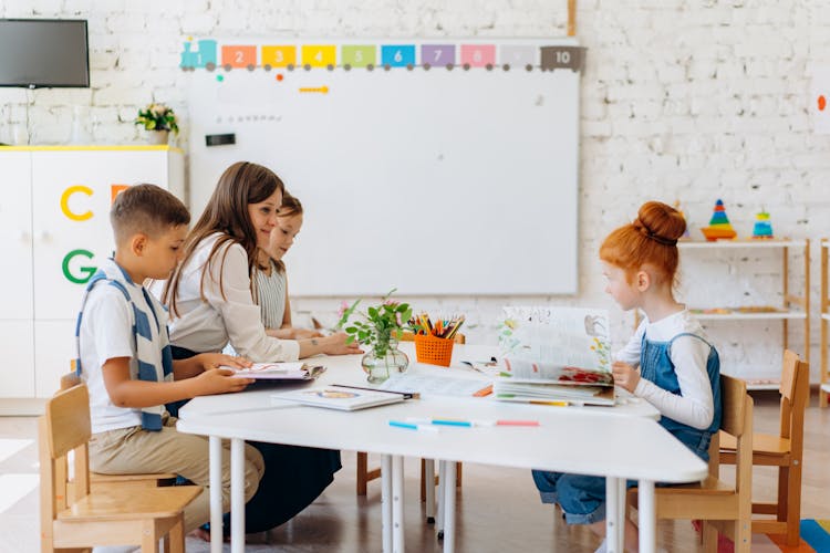 A Teacher Sitting With Her Students