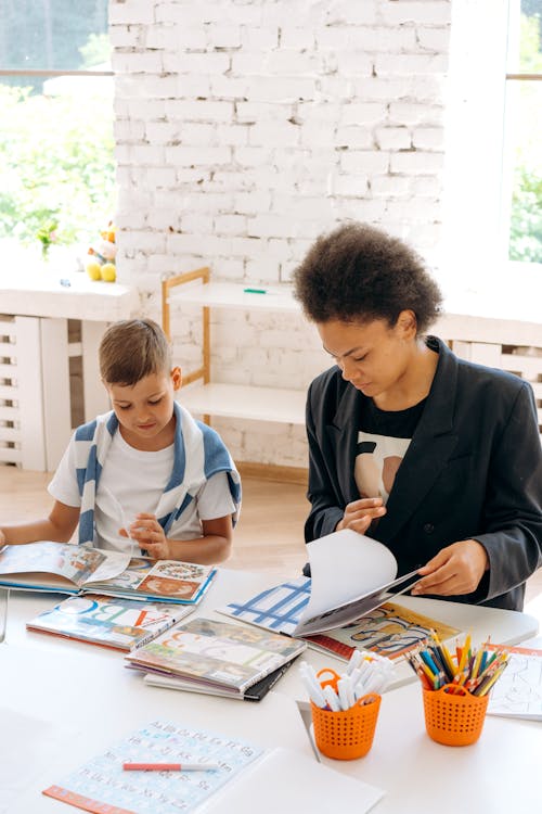 Woman beside a Boy Looking at the Books