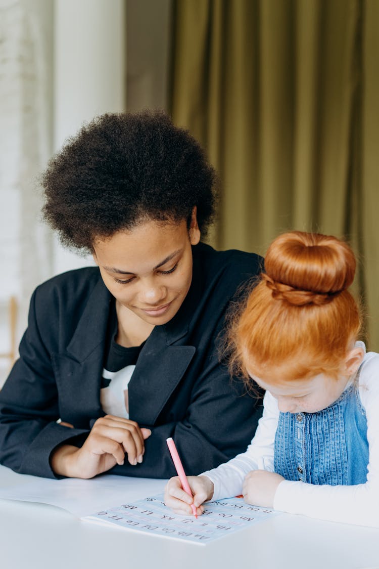 Woman In Black Blazer Teaching A Girl