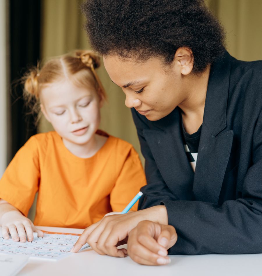 Teacher sitting beside a child during a workbook activity