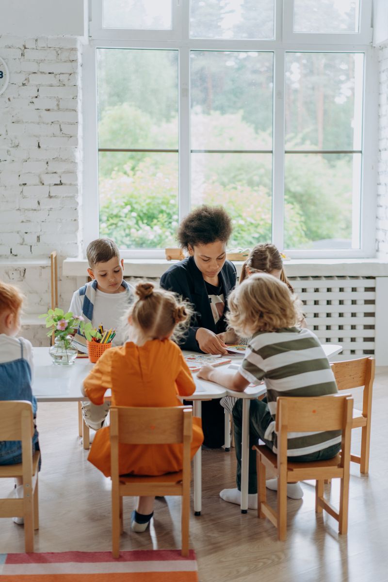 A teacher working with a small group of young students around one table