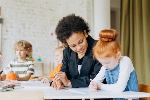 A Girl Writing On A Book Beside A Woman