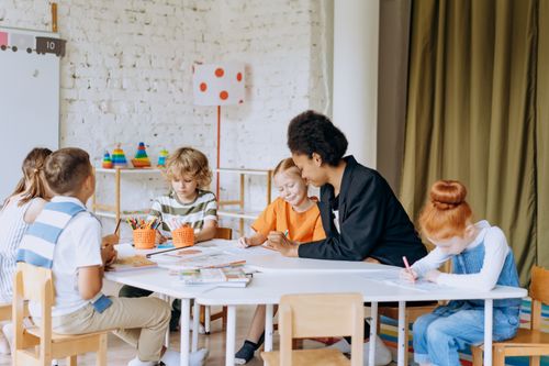 Free A teacher engaging with diverse children during a classroom activity, promoting education and learning. Stock Photo