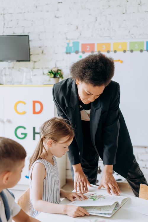 Free Teacher engaging with children in a colorful preschool classroom setting. Stock Photo