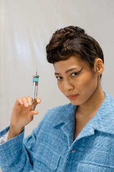 Stylish woman in blue suit holding syringe, in a laboratory setting.