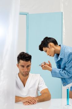 A healthcare professional prepares an injection for a patient in a modern clinical setting.