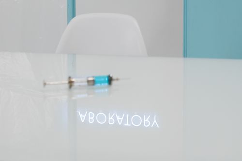 Free A syringe on a glass table with a laboratory reflection in a clean, clinical setting. Stock Photo