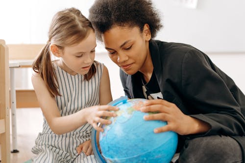 A Woman and a Girl Looking at a Globe