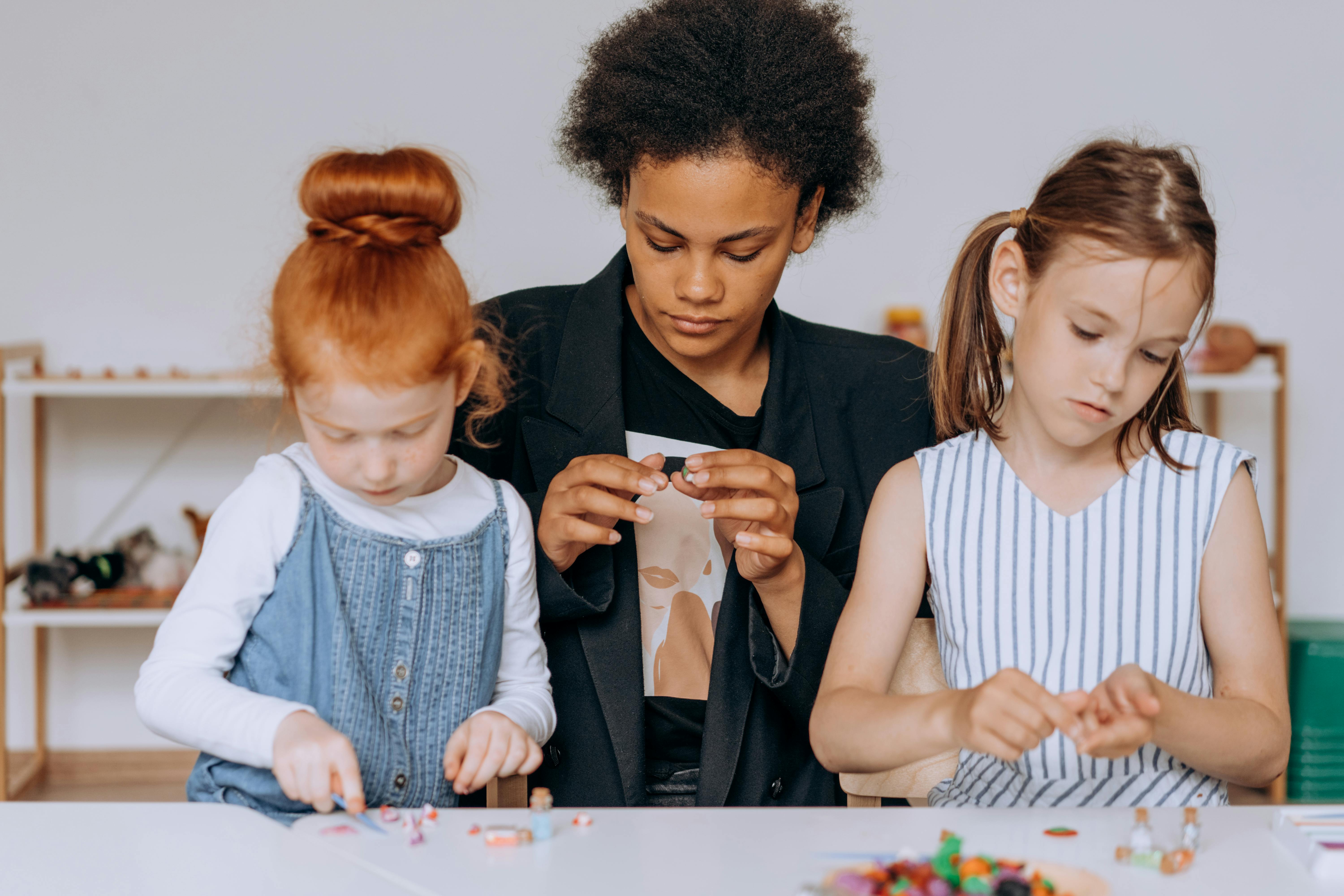 a woman sitting with the girls while holding toys