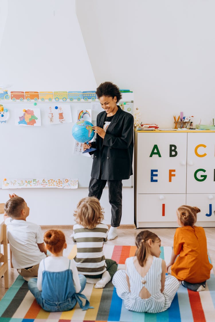 A Woman Teaching Children About The Globe