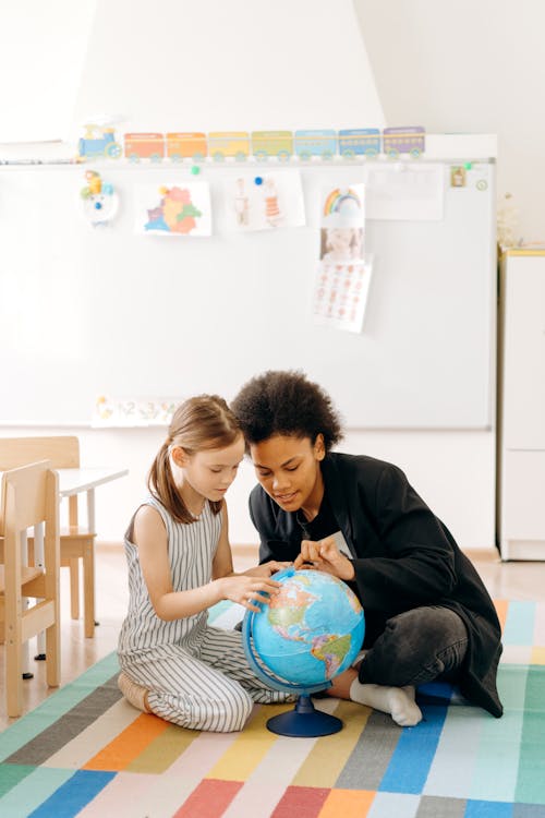 A Woman and a Girl Looking at the Rotating Earth Globe Map