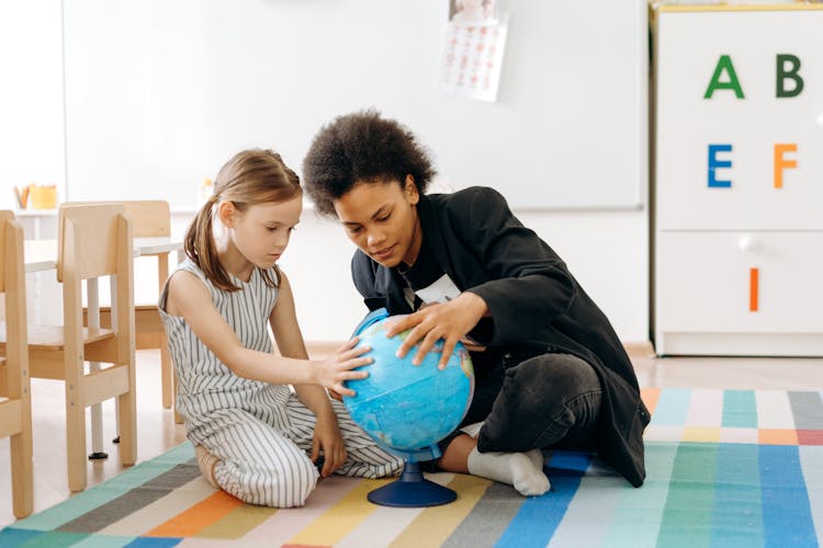 A Person And A Girl Looking At A Desk Globe