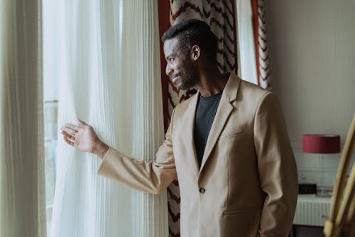 Man in Brown Suit Jacket Looking Outside the Window