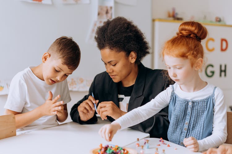 Teacher And Her Students Sitting At The Table