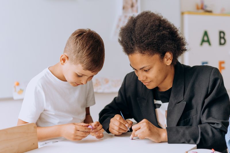 A teacher assisting a young student with a structured learning activity
