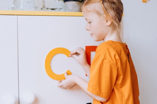 A Girl Sticking Colorful Letters on the White Board