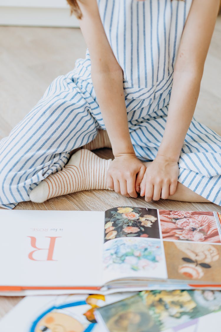 Photograph Of A Kid Sitting Near A Book