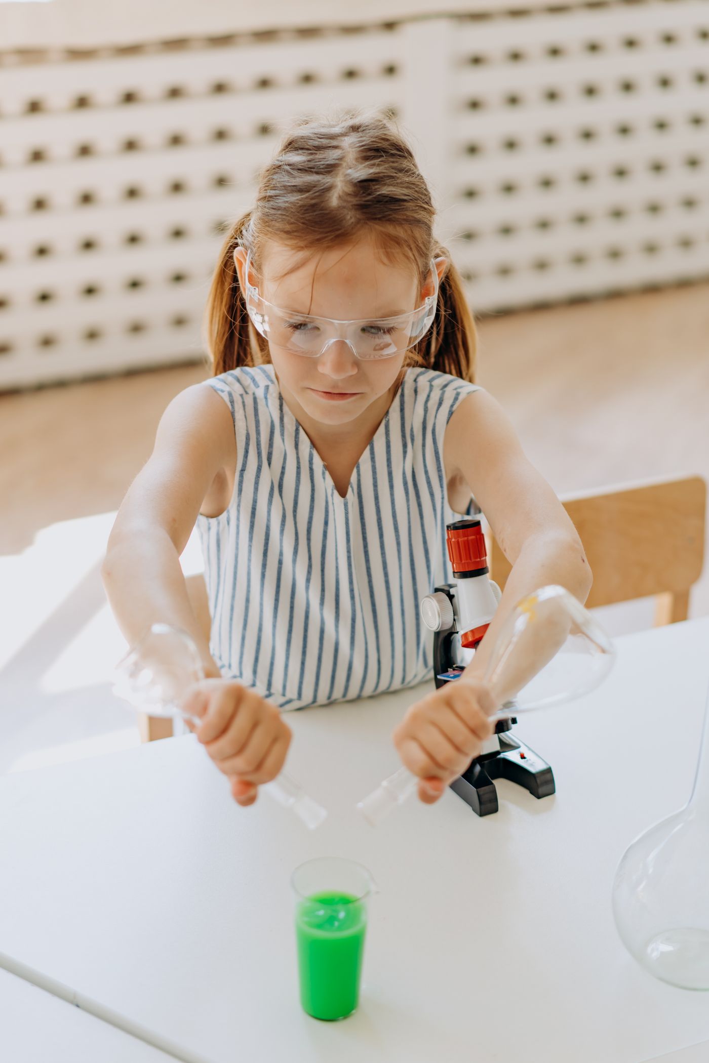 Child wearing safety glasses while working with a science experiment set