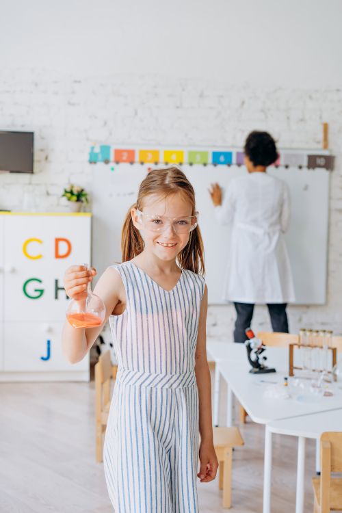 Free Child experimenting with beaker in science classroom, promoting education. Stock Photo