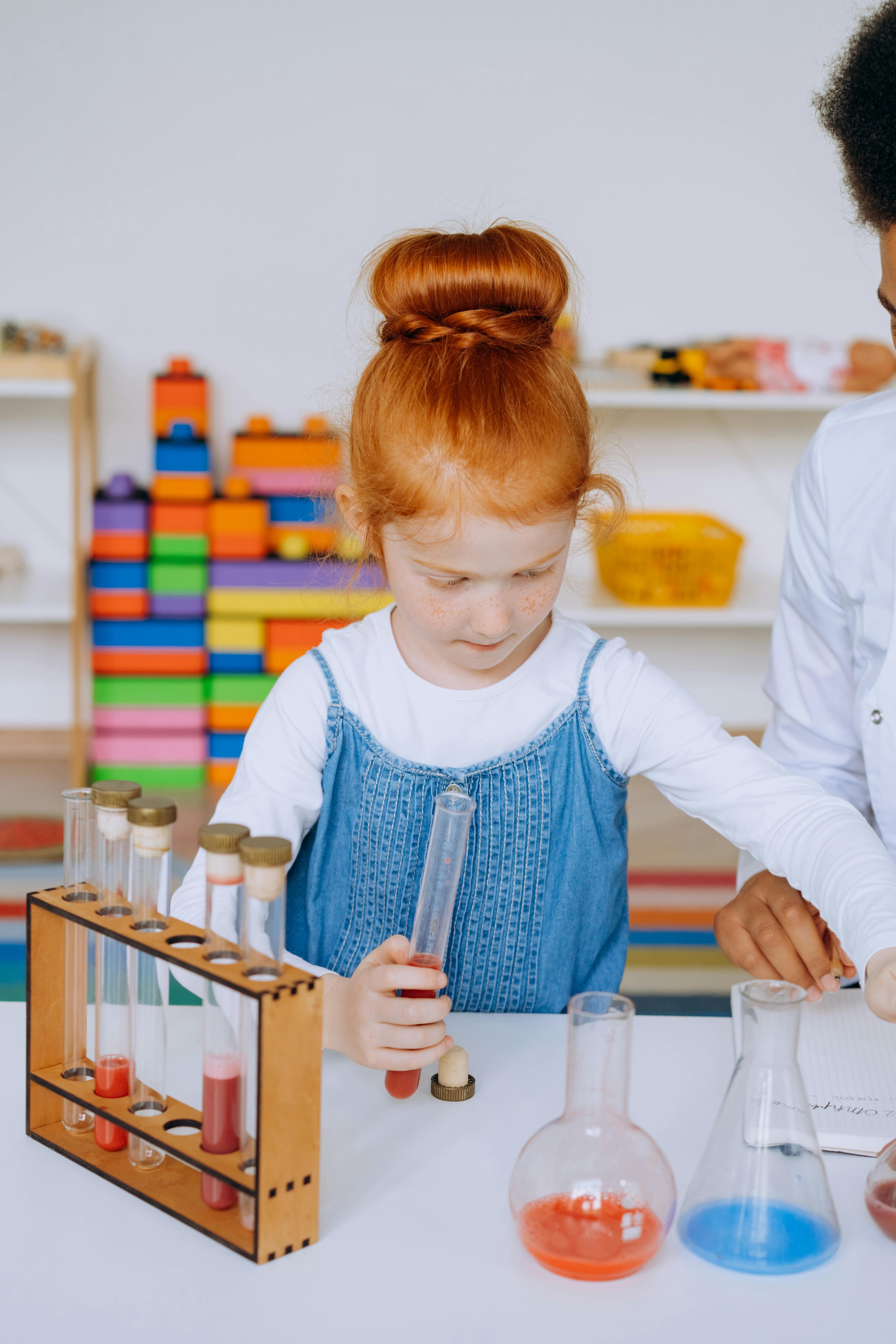 Child engaging in a science experiment with test tubes and flasks in an educational setting.