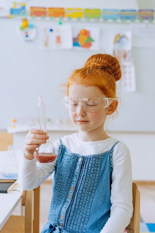 Free A child wearing safety goggles conducts a science experiment indoors, showcasing curiosity and learning. Stock Photo