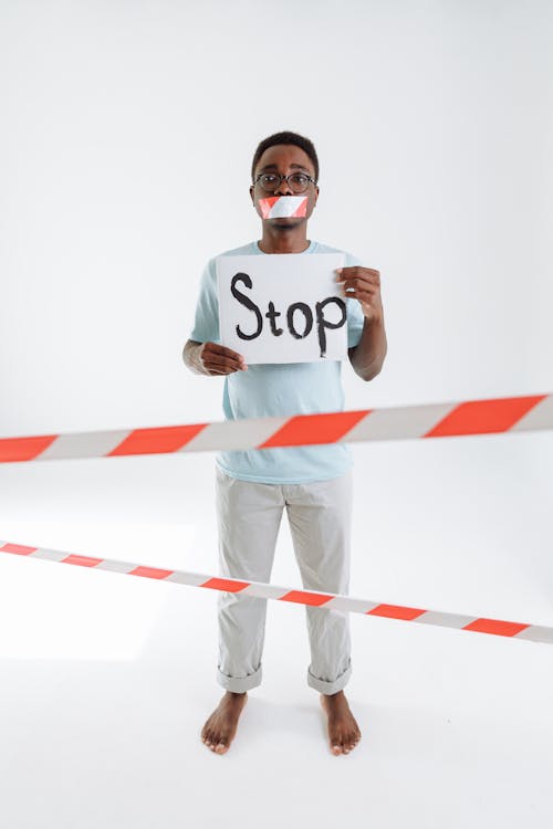 A Man with a Taped Mouth Holding a Sign