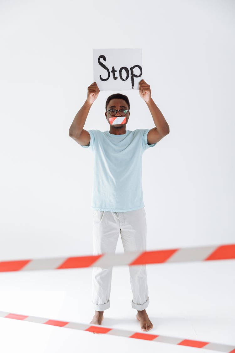  Man With Mouth Tape Holding A Stop Signage