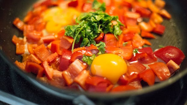 Close-up view of a colorful egg and bell pepper breakfast skillet with herbs.