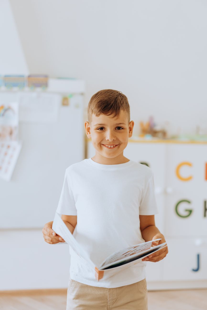Cheerful boy holding a book in classroom