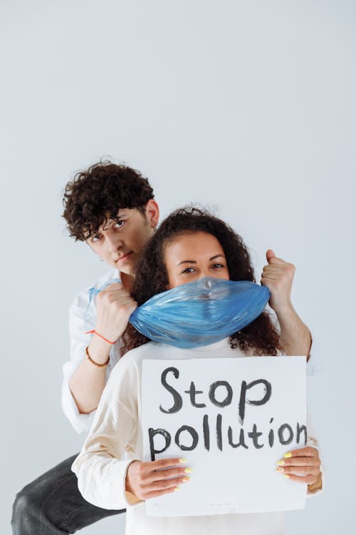 Man Holding a Plastic and Woman with a Stop Pollution Sign